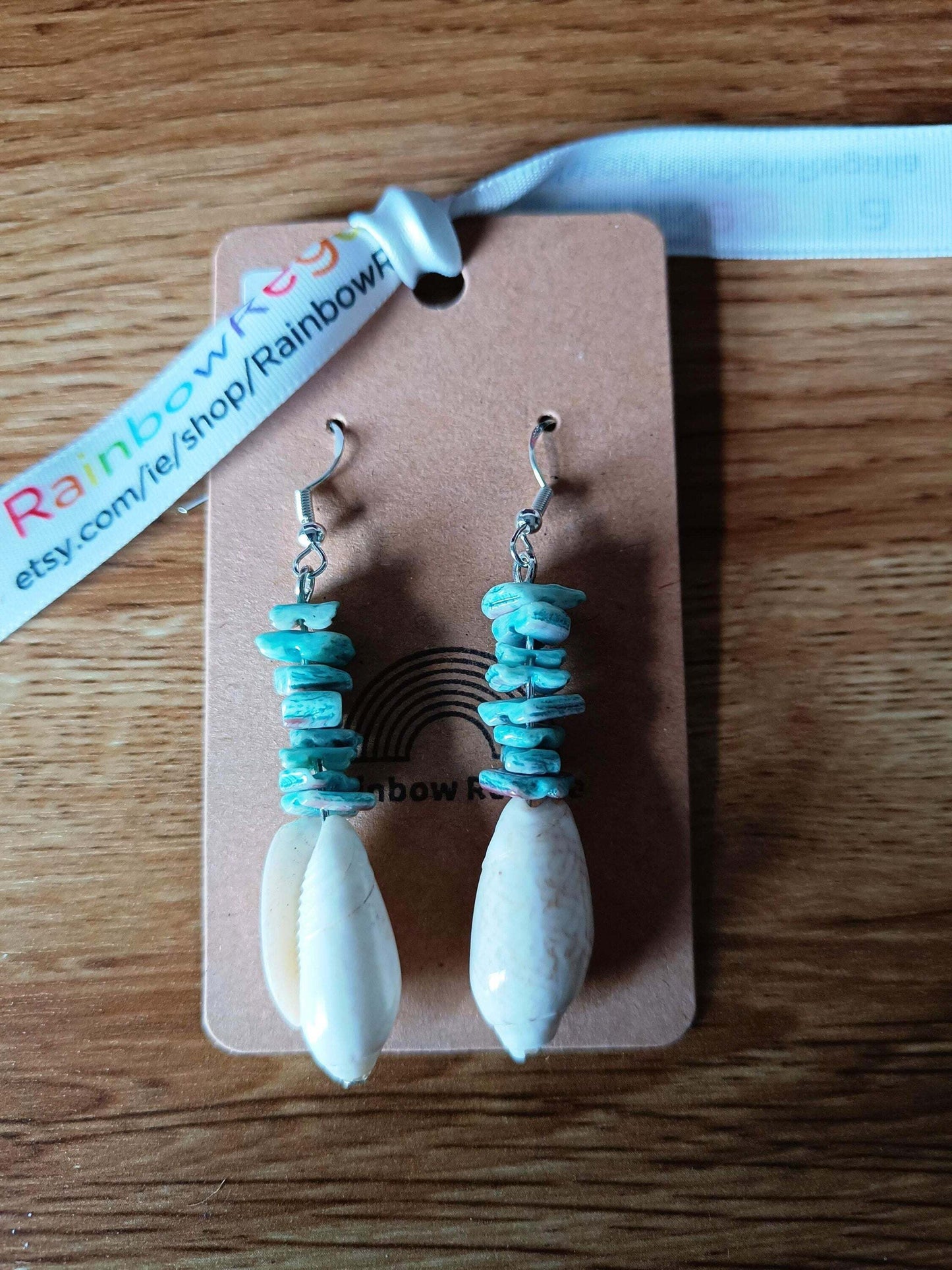 Turquoise and white shell dangle earrings on a display card.