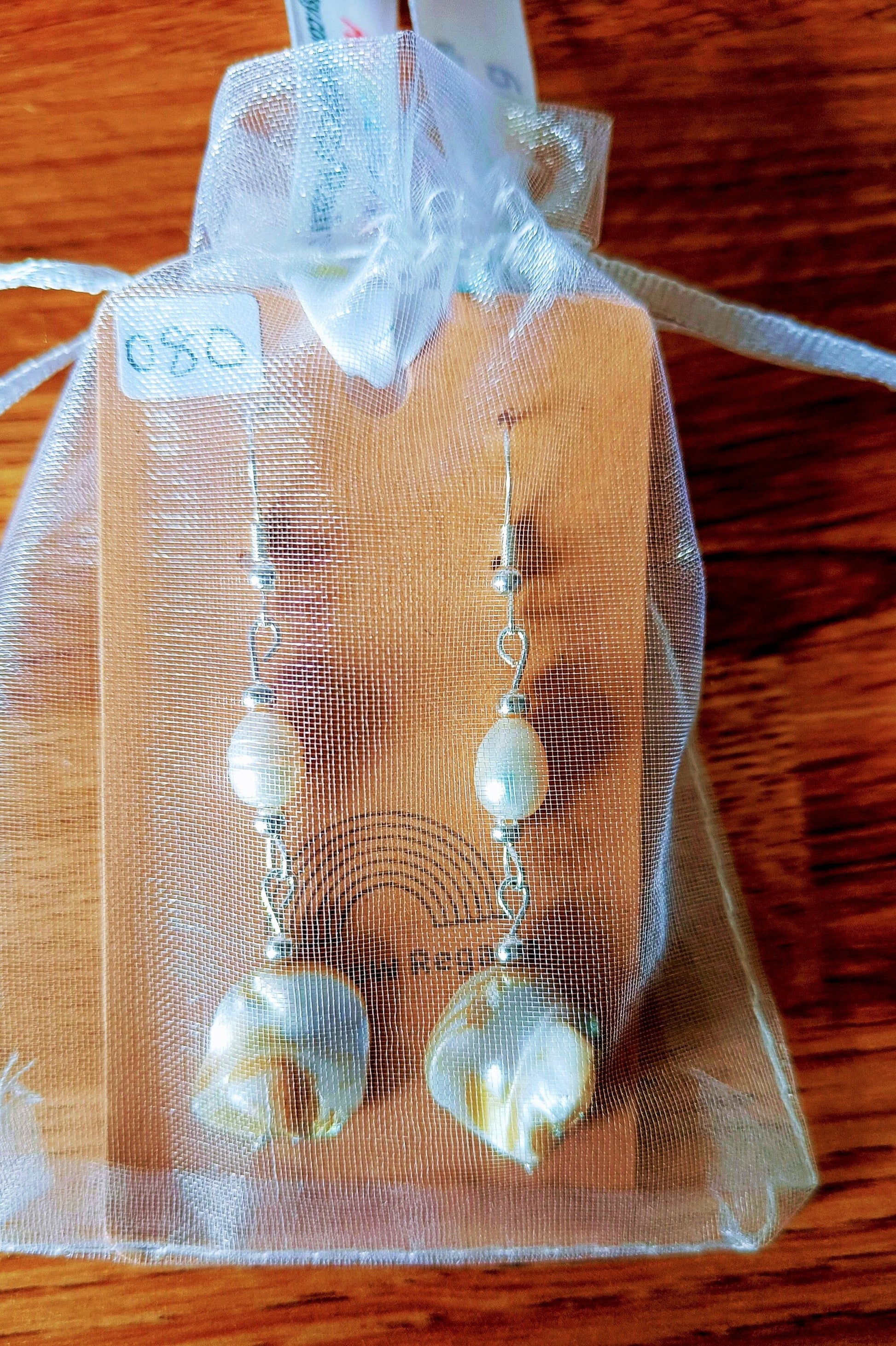 Long freshwater pearl earrings with mother of pearl dangle and silver-plated beads displayed on a decorative card.