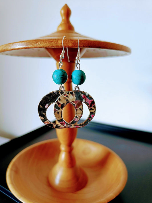 Turquoise hoop earrings with repurposed stone beads and antique silver hoops on wooden display.