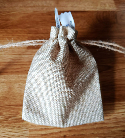 Burlap gift bag containing Rainbow Umbrella Hoops earrings.