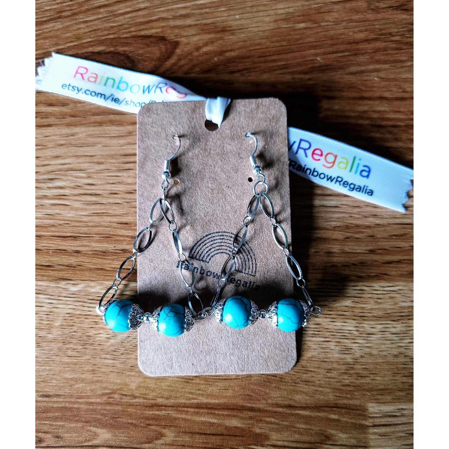 Silver and turquoise chandelier earrings with turquoise beads and silver chain on a wooden background.