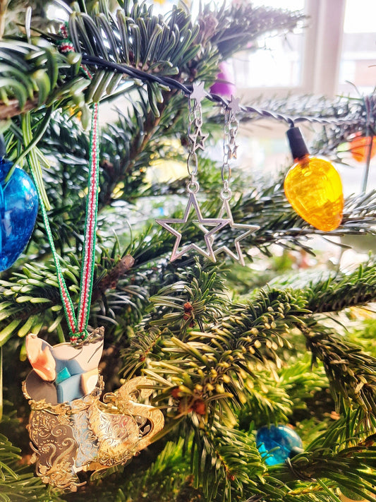 Eleanor Star Earrings hanging on a Christmas tree, featuring stainless steel chain and silver-plated star charms.