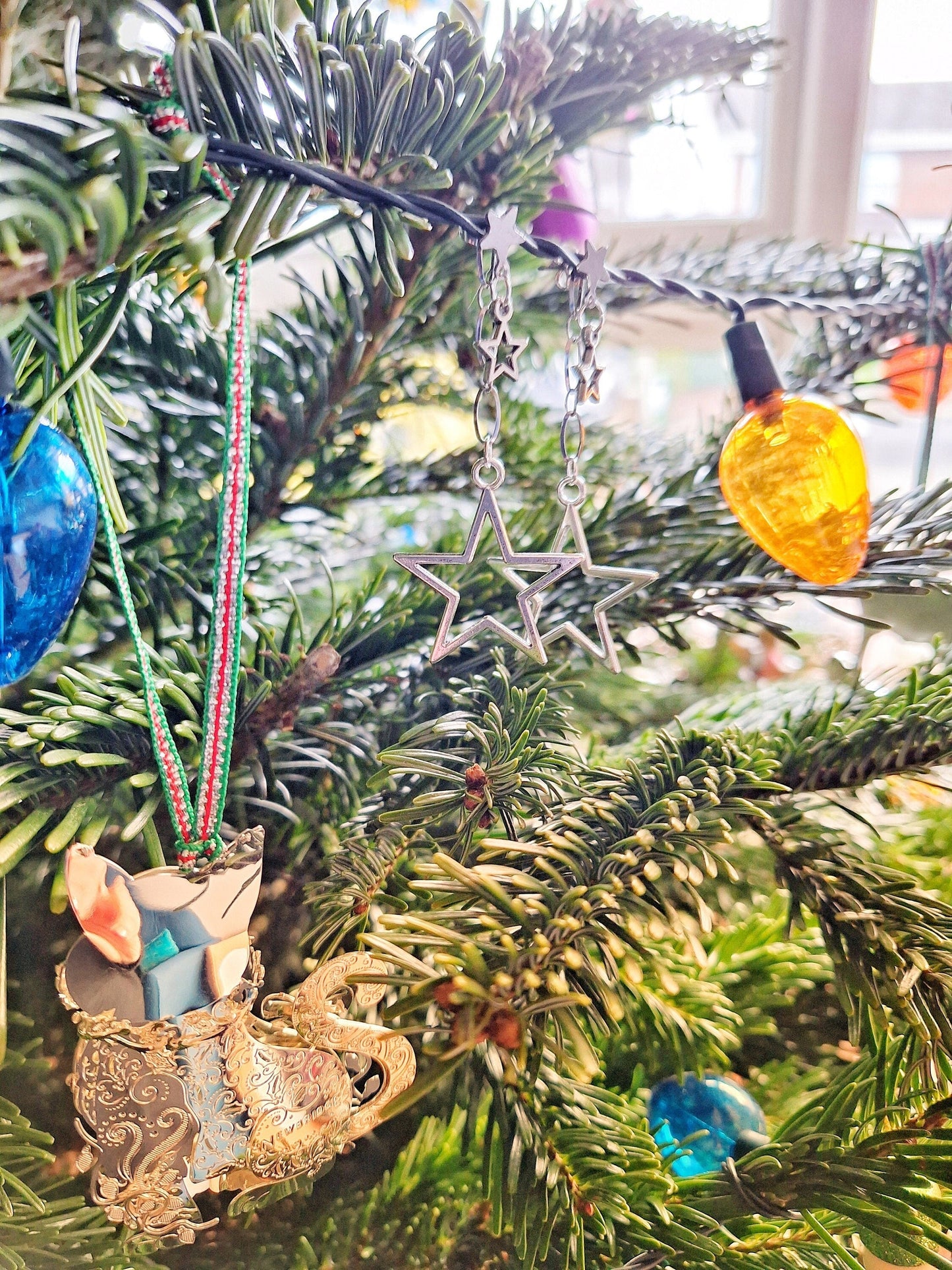 Eleanor Star Earrings hanging on a Christmas tree, featuring silver-plated star charms.