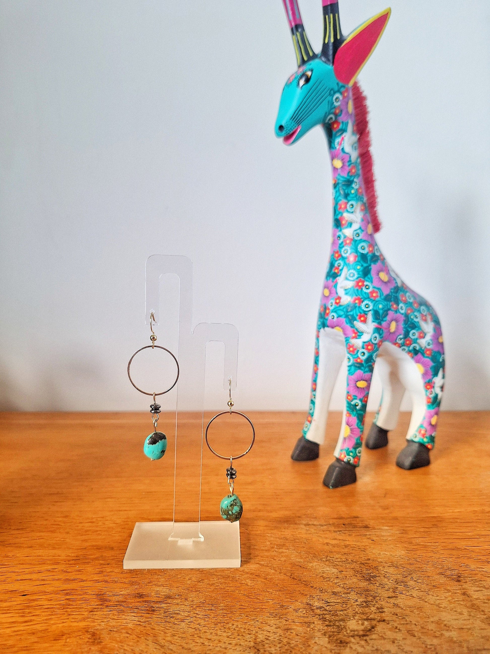 Sofia Turquoise Drop Earrings with gold-plated accents and black mirrored discs displayed on a stand.