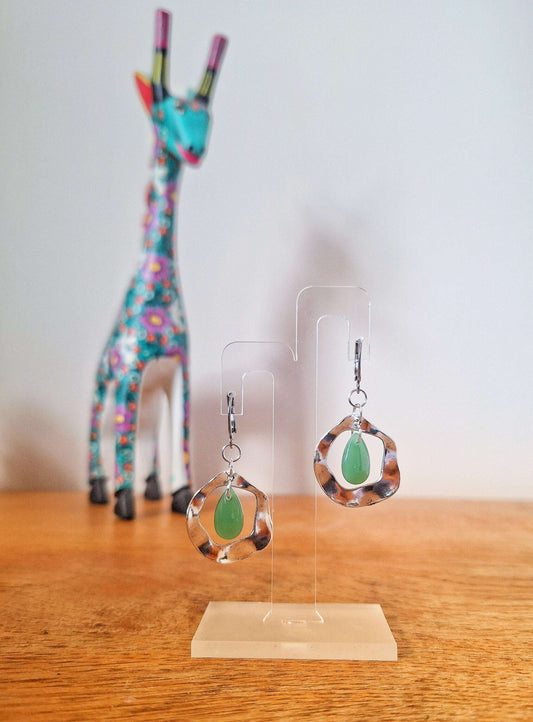 Jade green earrings with teardrop beads on stainless steel huggie hoops displayed on a stand.