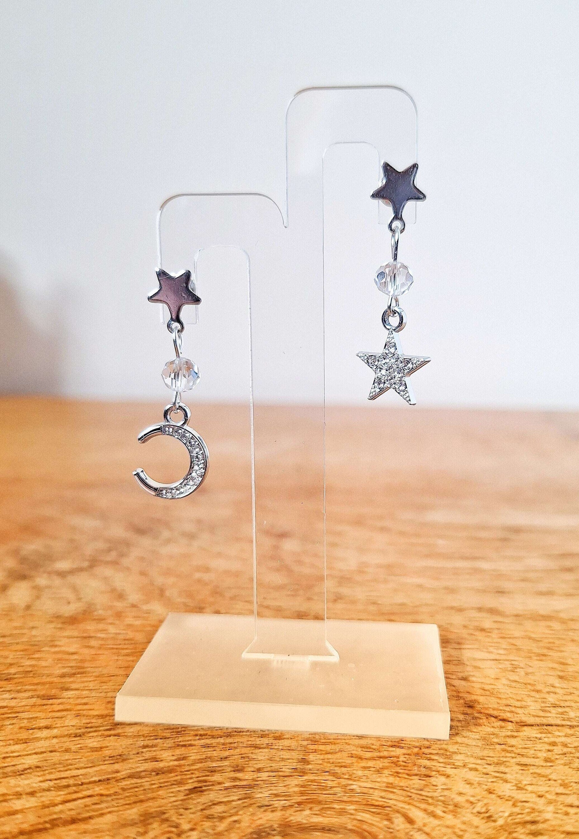 Nova Moon and Star Earrings with silver plated charms and crystal beads, celestial design, on clear stand.