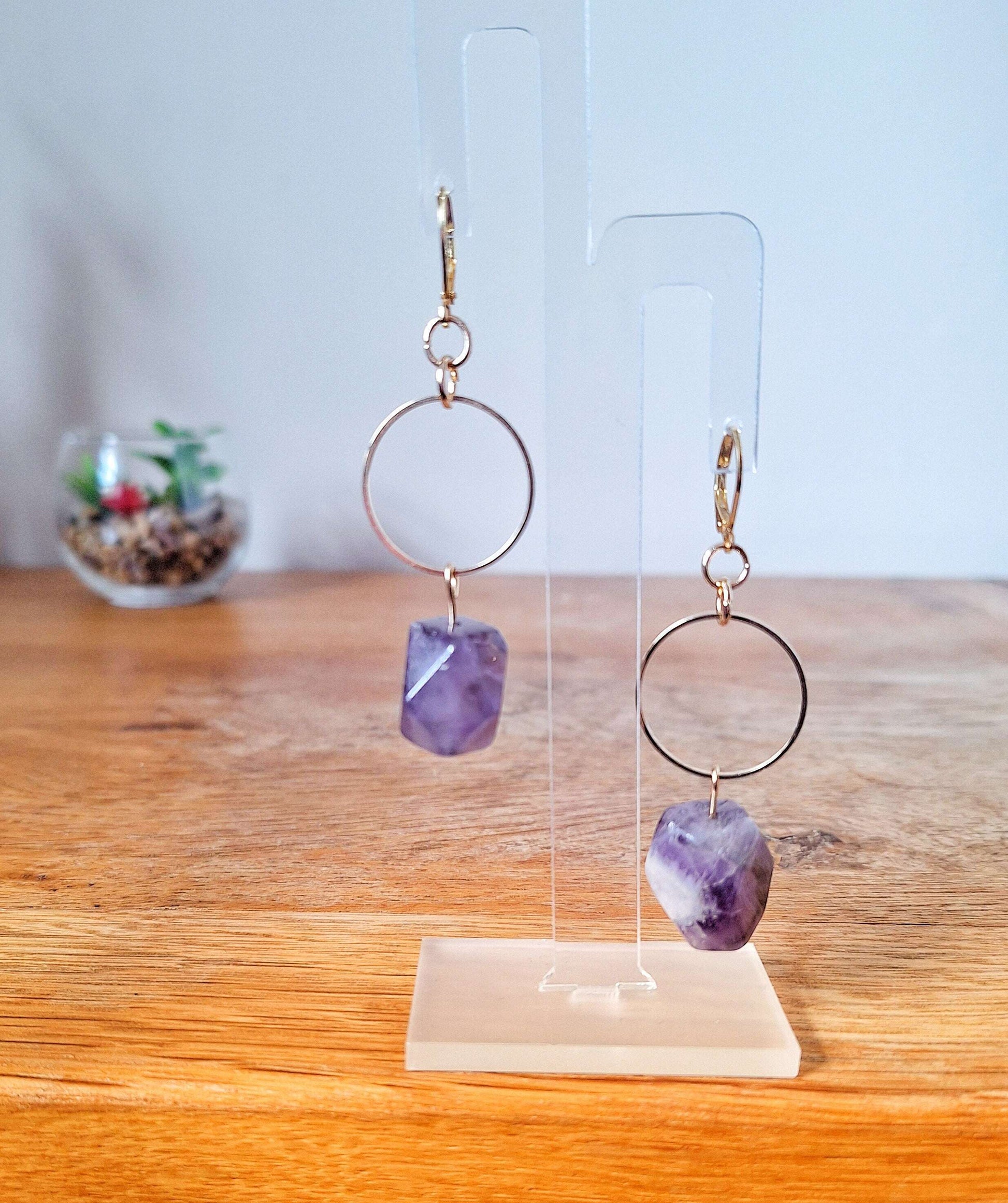 Florence Amethyst Earrings with raw amethyst stones and gold-plated lever back ear wires on a display stand.