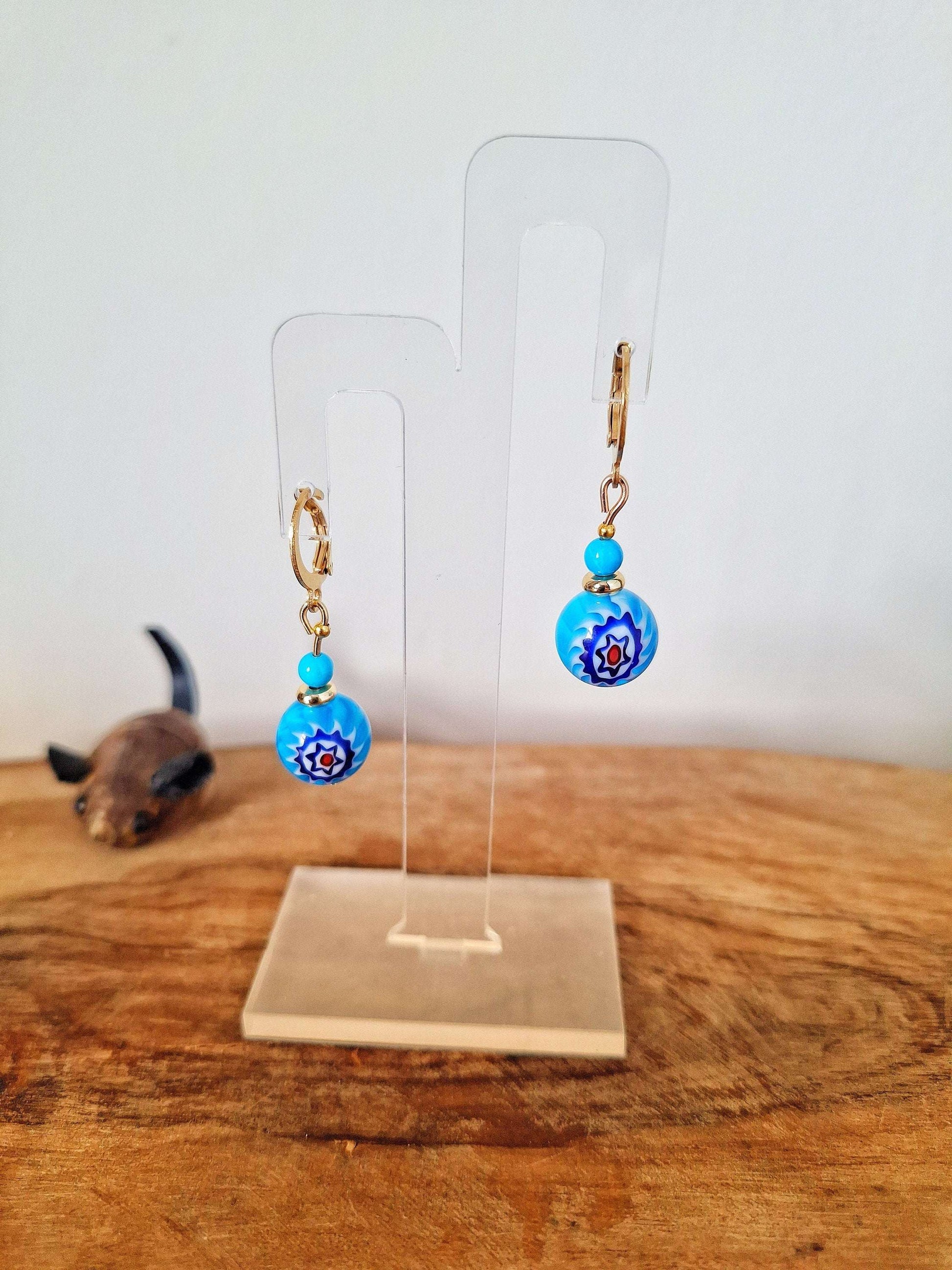 Millefiori glass bead huggies with gold-plated findings and colorful beads on display stand.