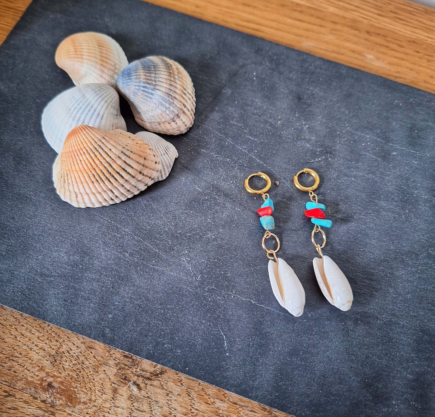Ariel turquoise and coral shell earrings with gold-plated hoops, paired with seashells on a black surface.