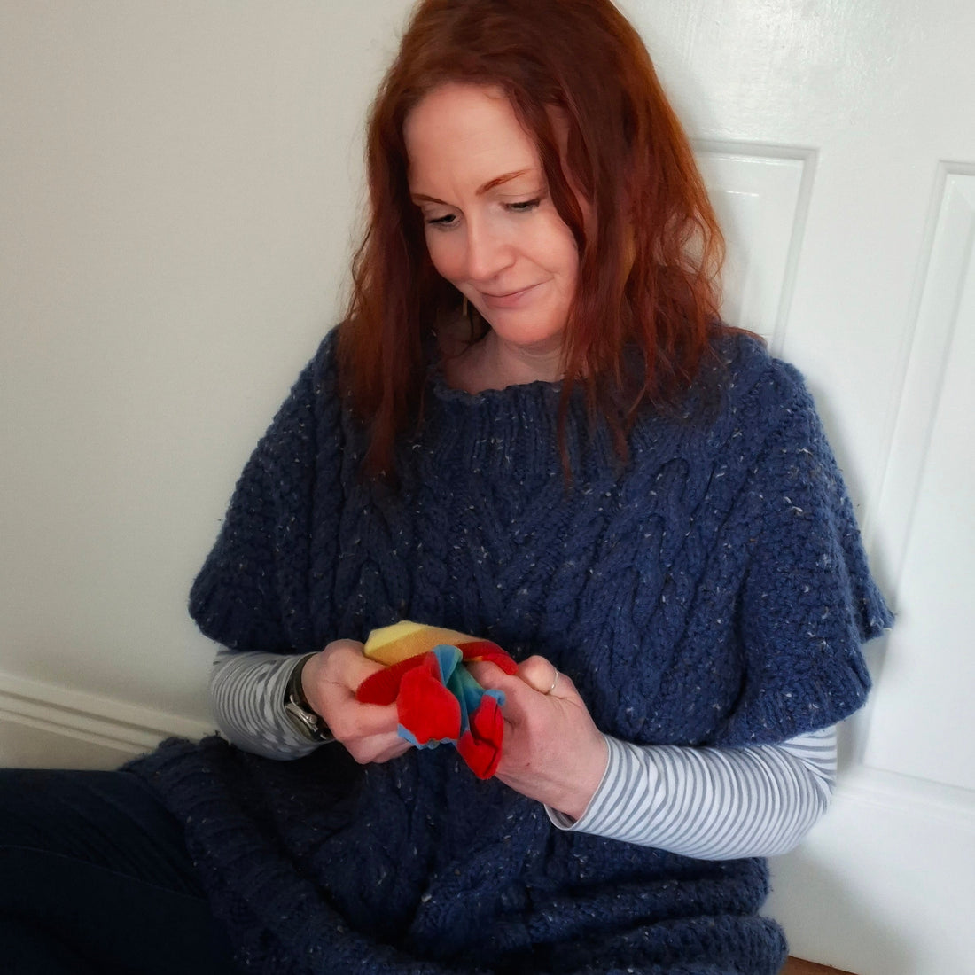 A redheaded woman folding rainbow socks