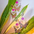Butterfly-shaped earrings with colorful beads on a leaf background
