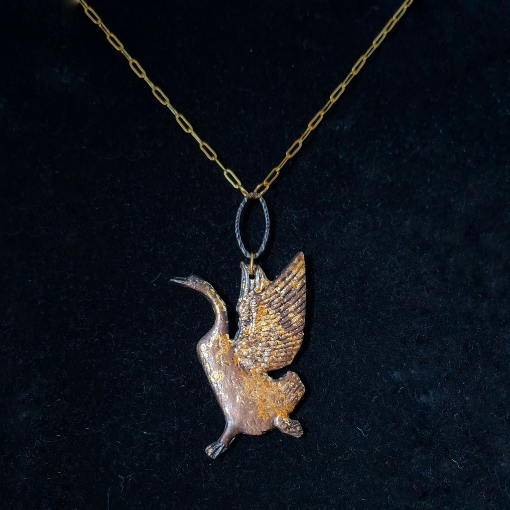Bird-shaped pendant on a chain against a dark background