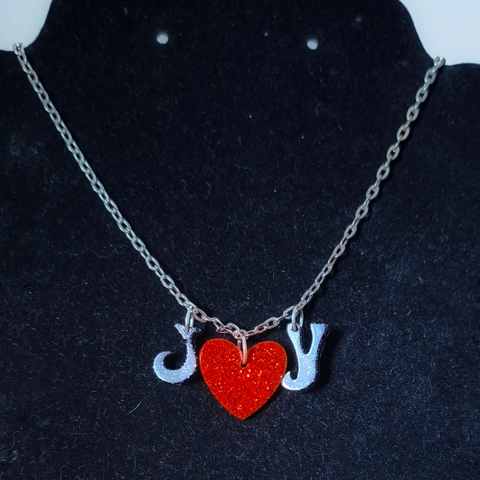 Necklace with heart and letter charms on a dark background