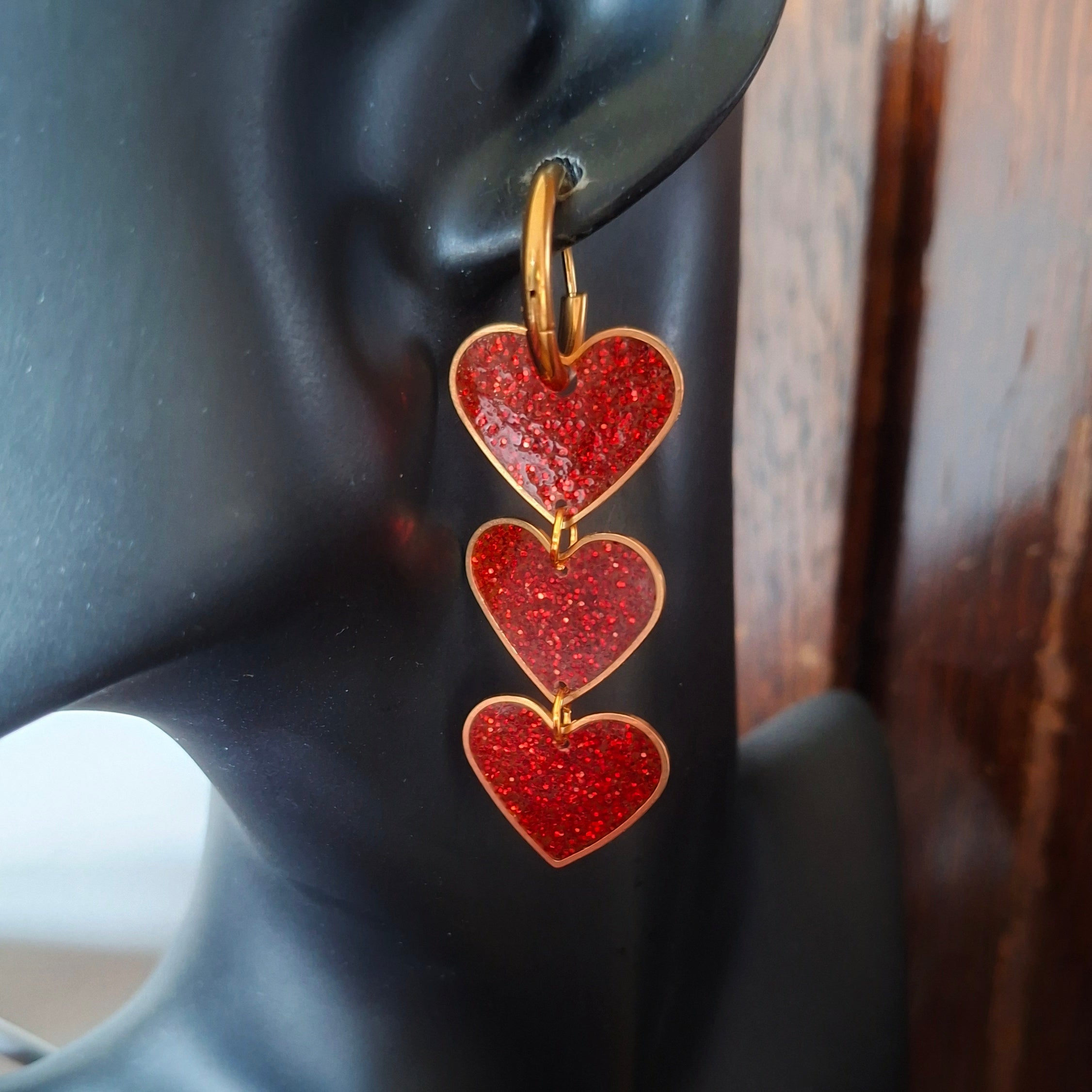 Red heart-shaped earrings on a black mannequin ear