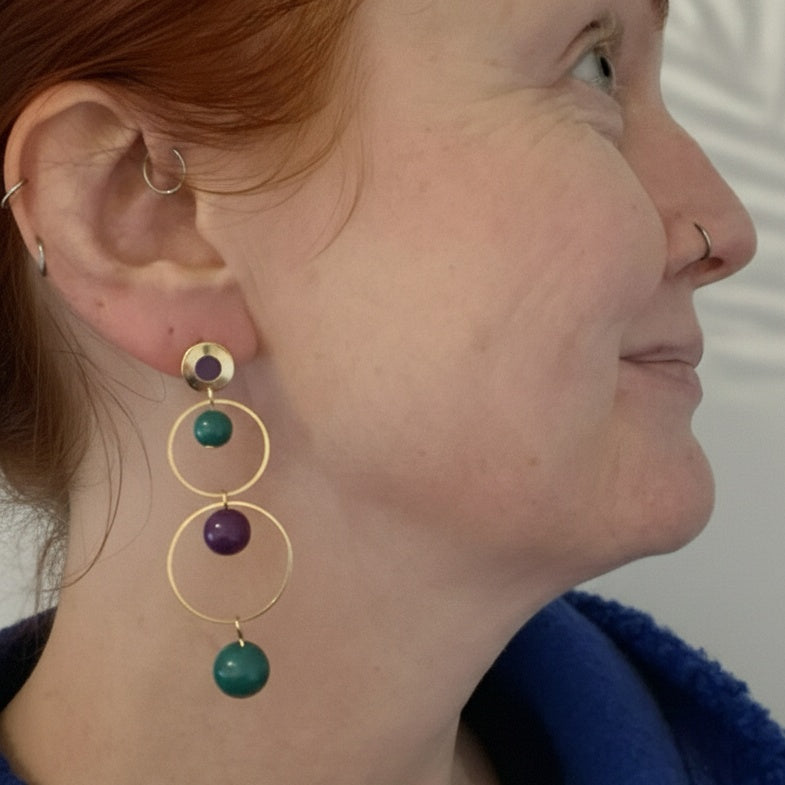 Eleanor wearing gold earrings with green and purple beads. Handmade by RainbowRegalia, Greystones, Co. Wicklow.