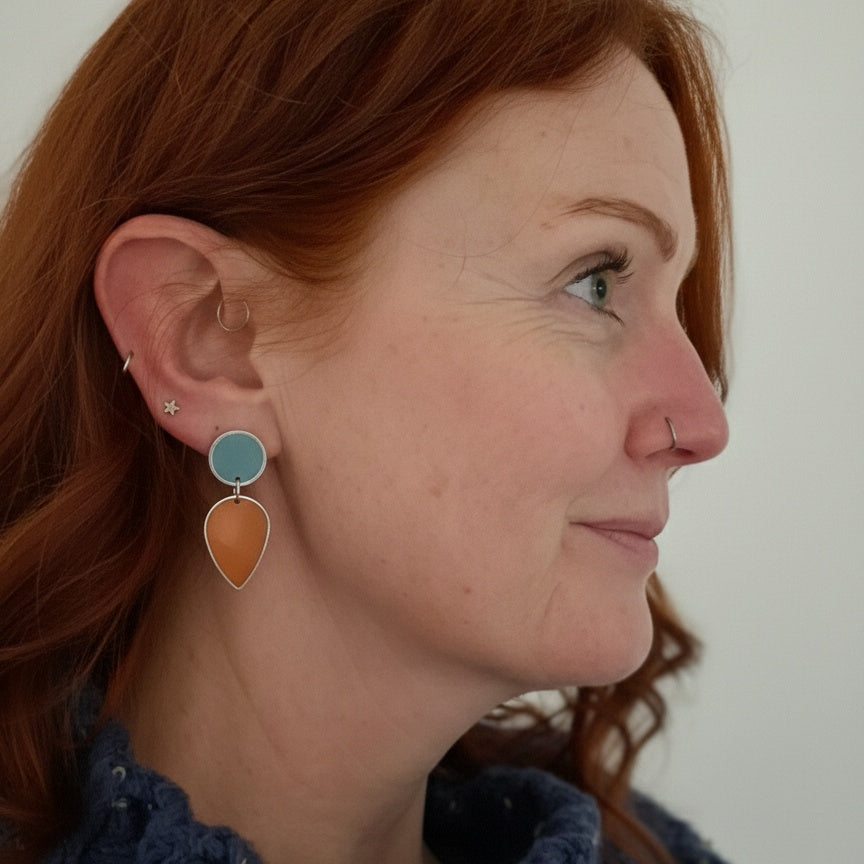 Pair of earrings with turquoise and orange teardrop shapes. Gold or silver finish.