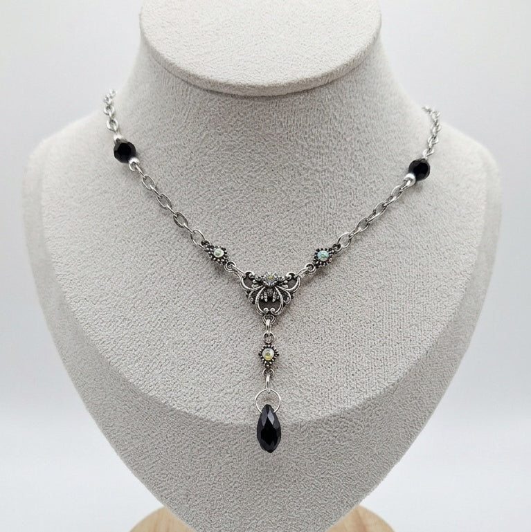 Silver coloured necklace made with black beads and vintage pieces