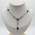 Silver coloured necklace made with black beads and vintage pieces