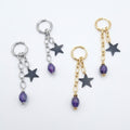 Cosmic Renegade Earrings feature repurposed purple glass beads and matt black stars on stainless steel huggies.