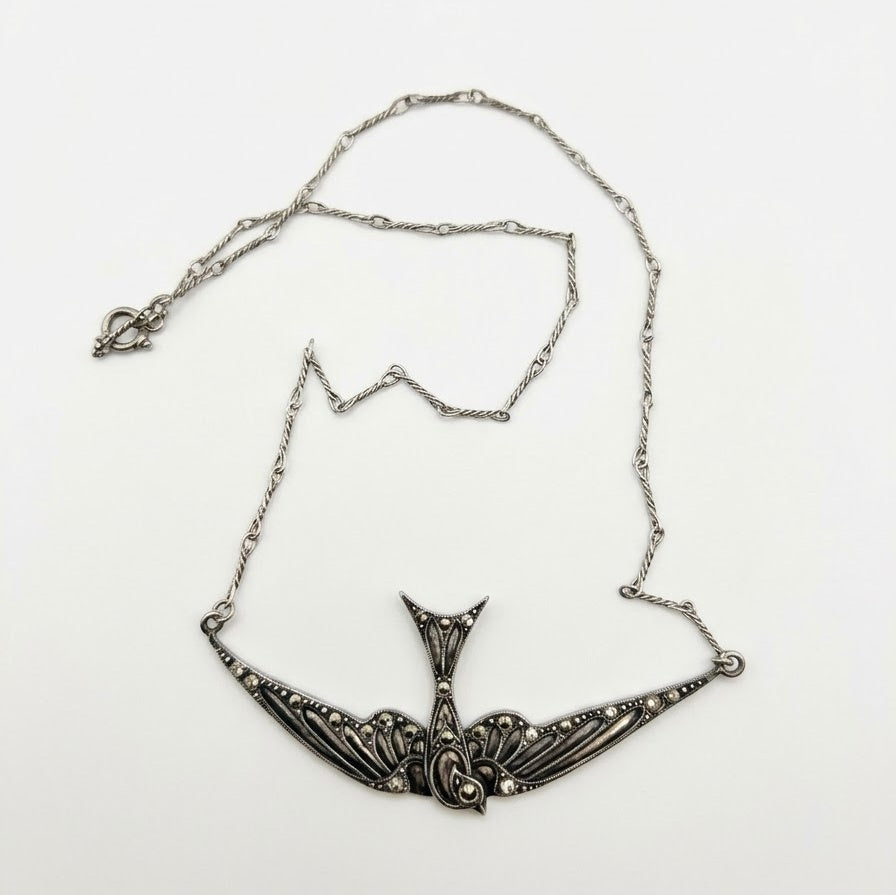 An antique-style silver necklace featuring a highly detailed, swallow pendant with filigree patterns and small clear stones, displayed on a clean white background.