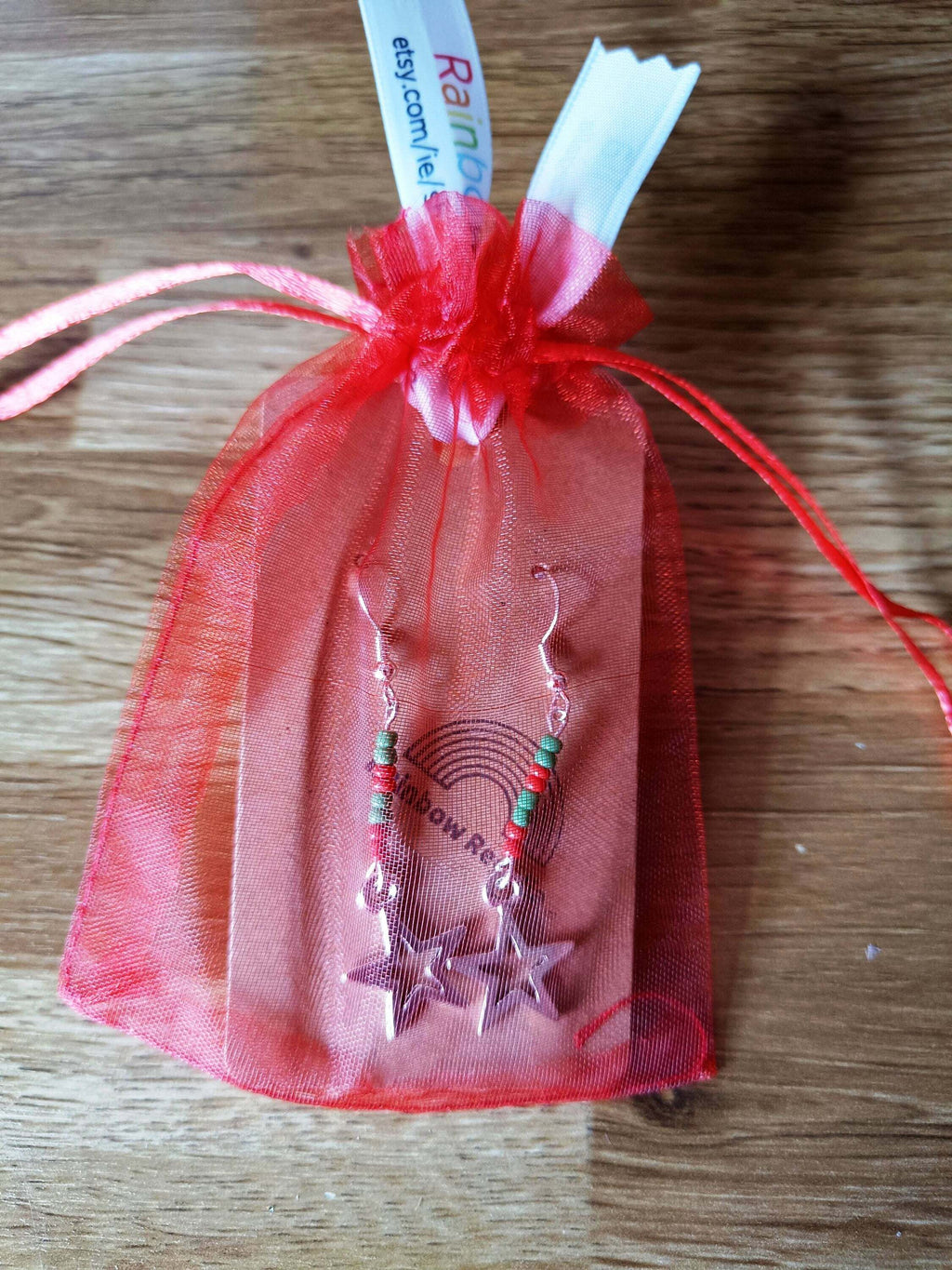 Red and green star earrings in festive packaging, crafted from repurposed glass beads.