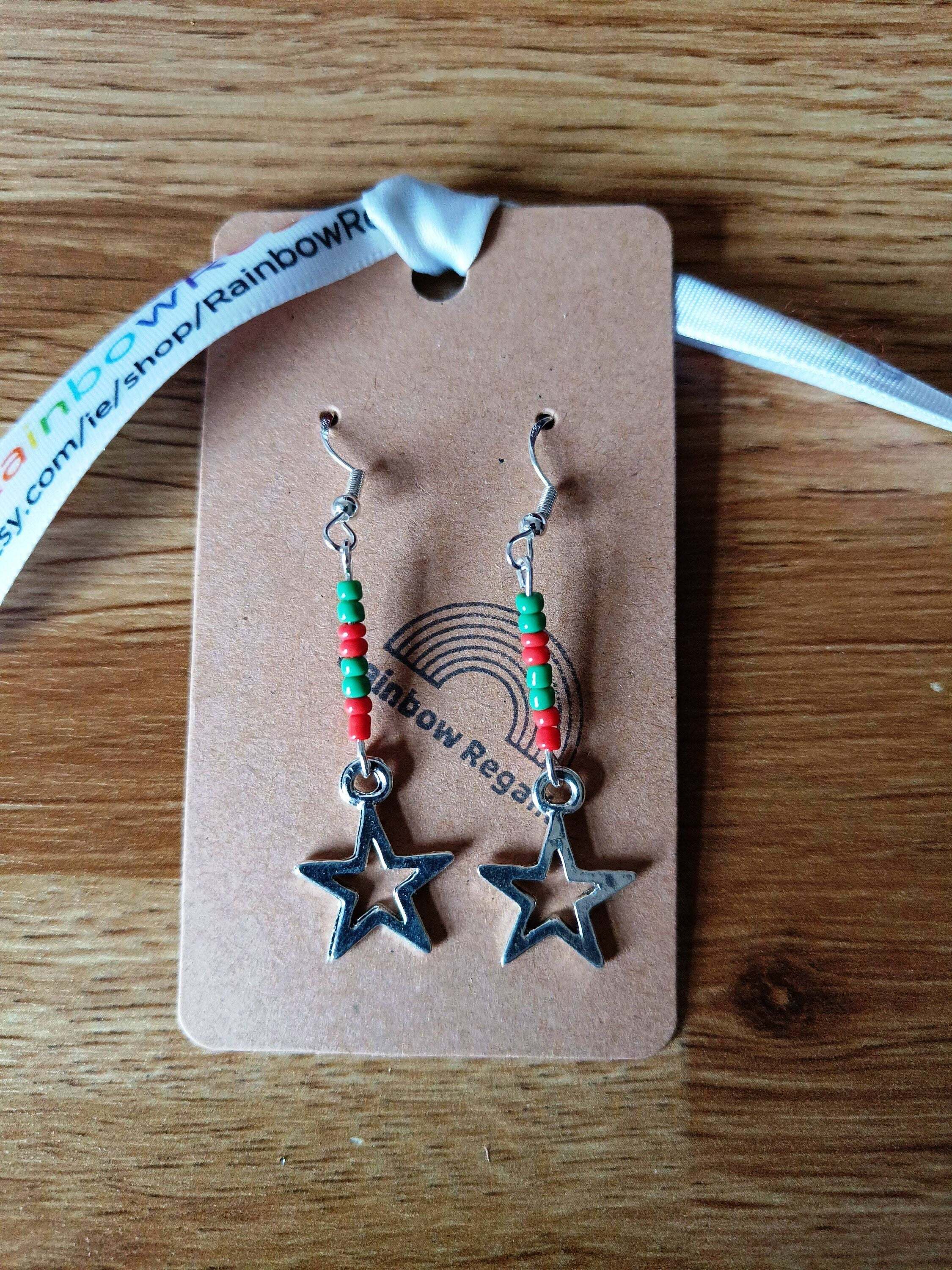 Red and green star earrings with glass seed beads on a rustic display card.