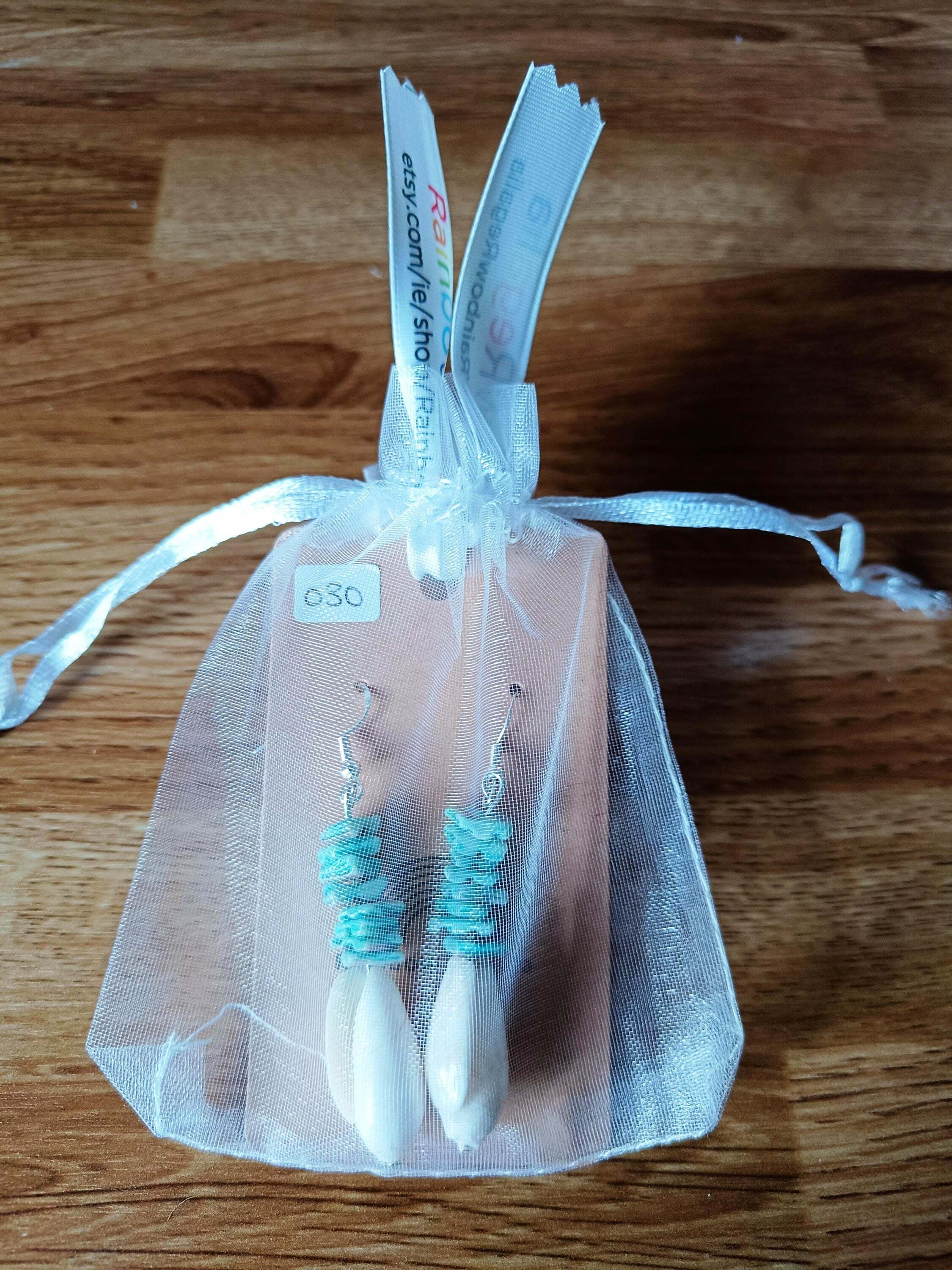 Turquoise and white shell dangle earrings in a sheer gift bag.
