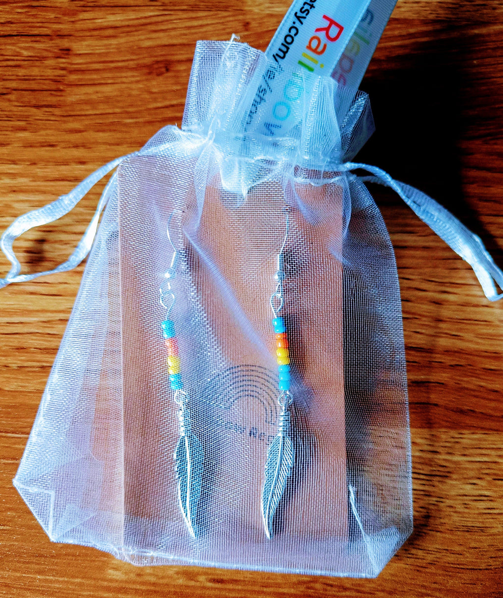 Multicolour Feather Earrings made with glass seed beads and antique silver feathers, displayed in a decorative pouch.