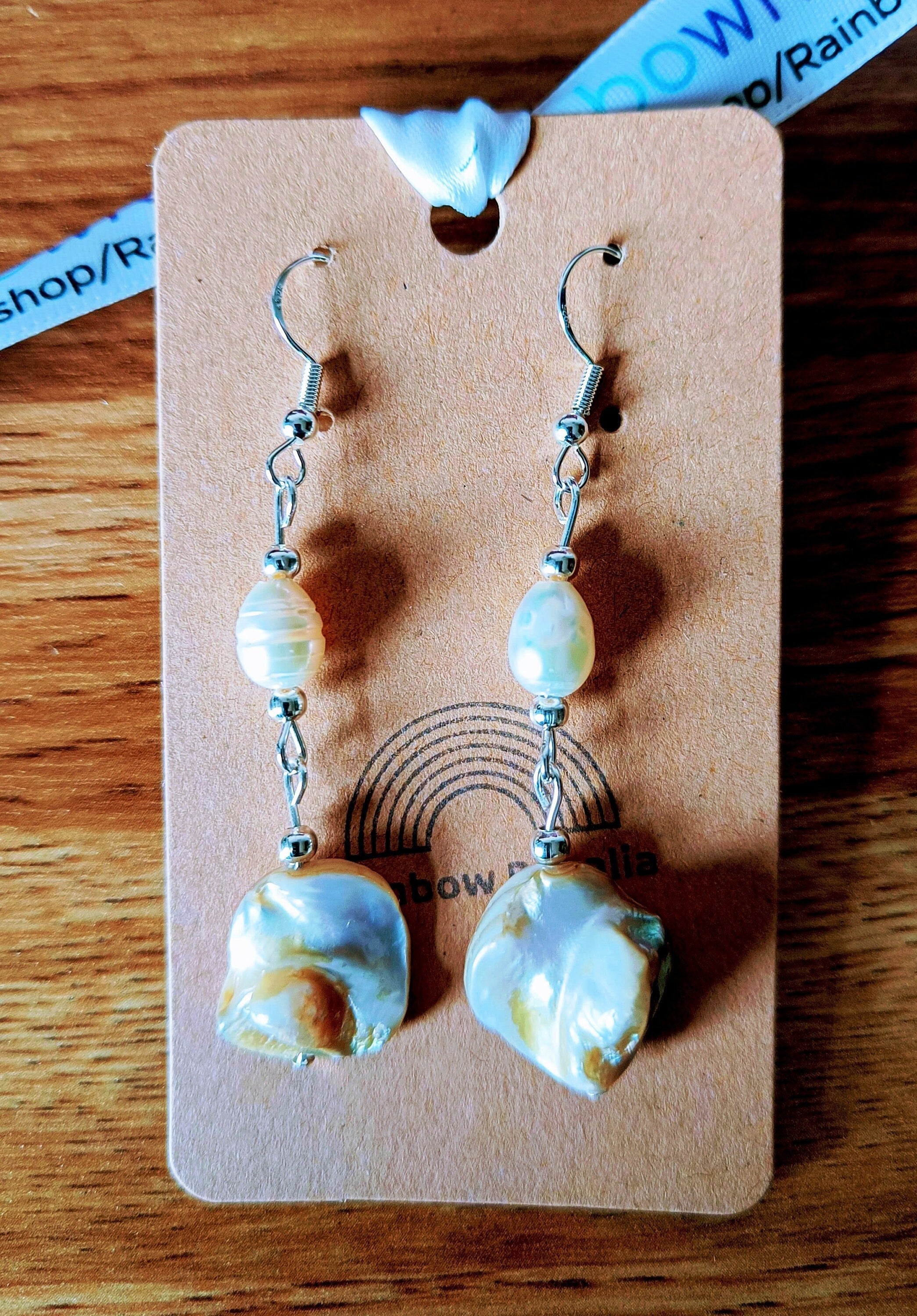 Long freshwater pearl earrings with mother of pearl and silver-plated beads on a display card.