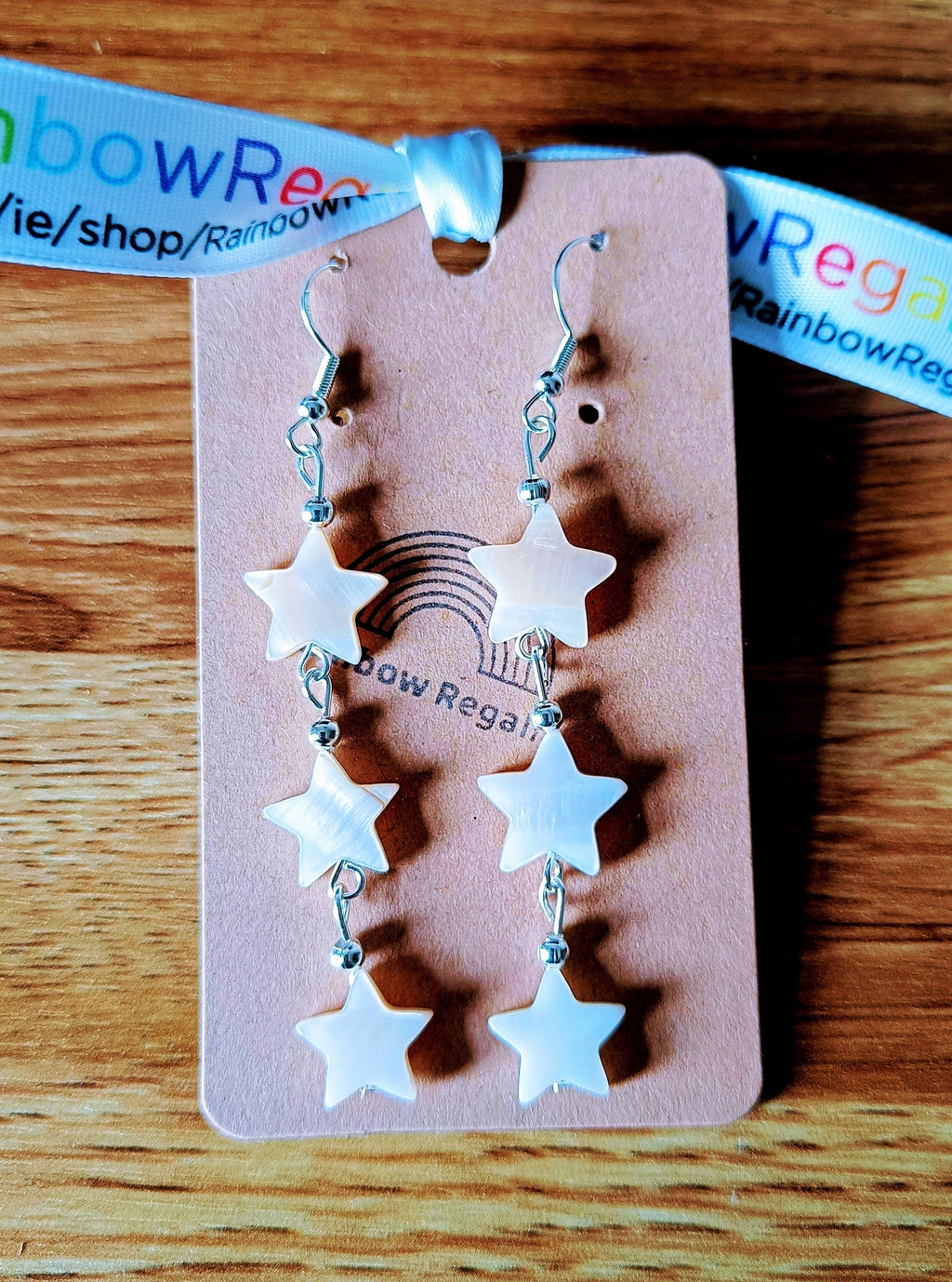 Maurea Mother of Pearl star silver earrings with white shell star beads on a display card.