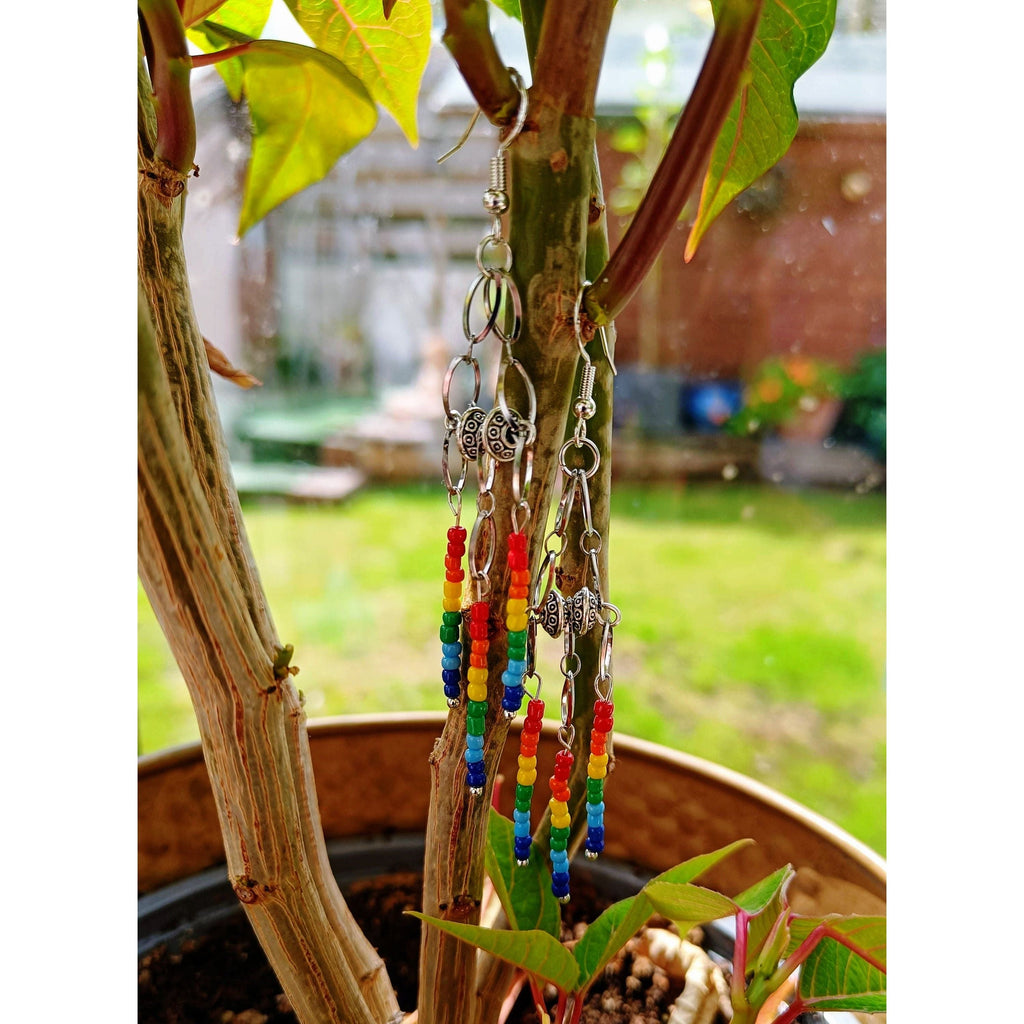 Rainbow chandelier earrings with glass seed beads and Tibetan silver accents hanging from tree.