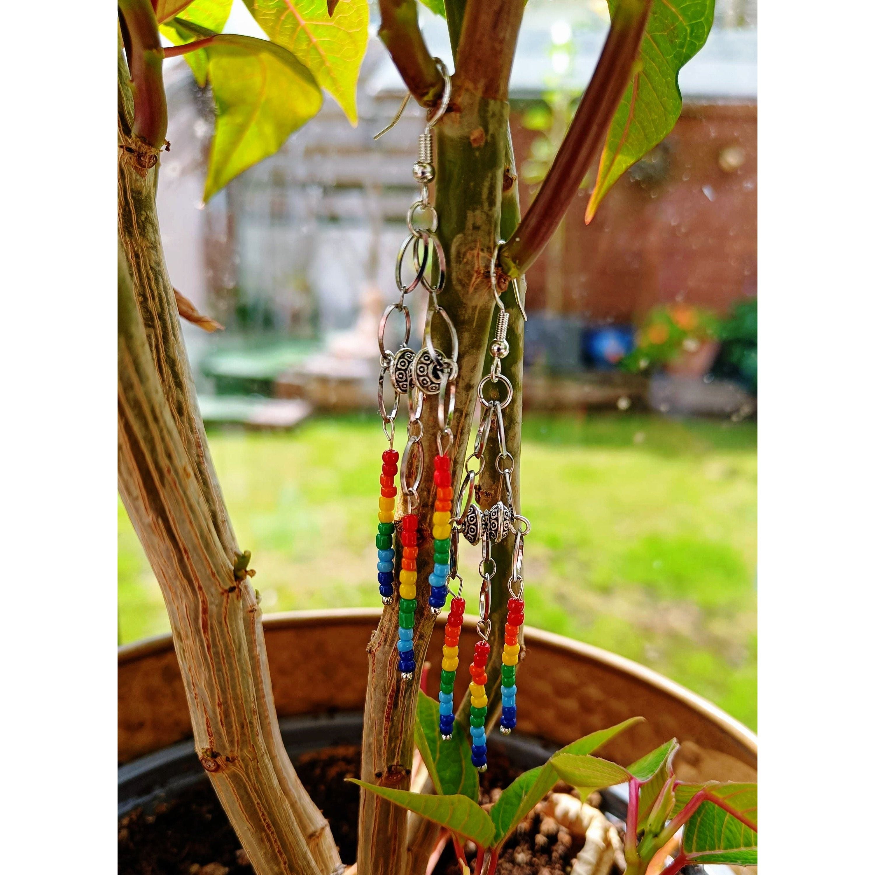 Rainbow chandelier earrings with glass seed beads and Tibetan silver accents hanging from tree.