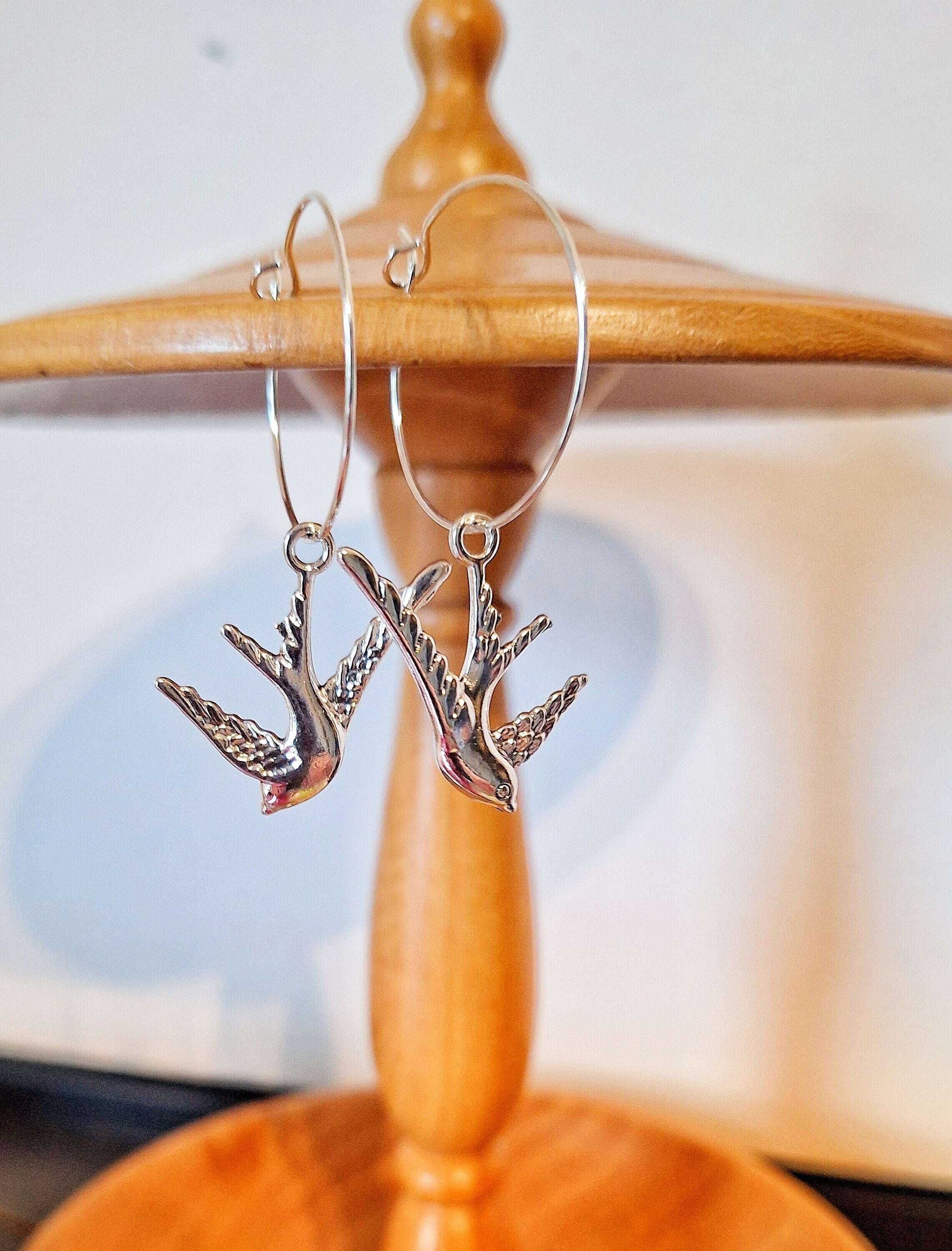 Silver swallow hoops with graceful bird charms, elegant silver-colored brass design, versatile jewelry accessory.