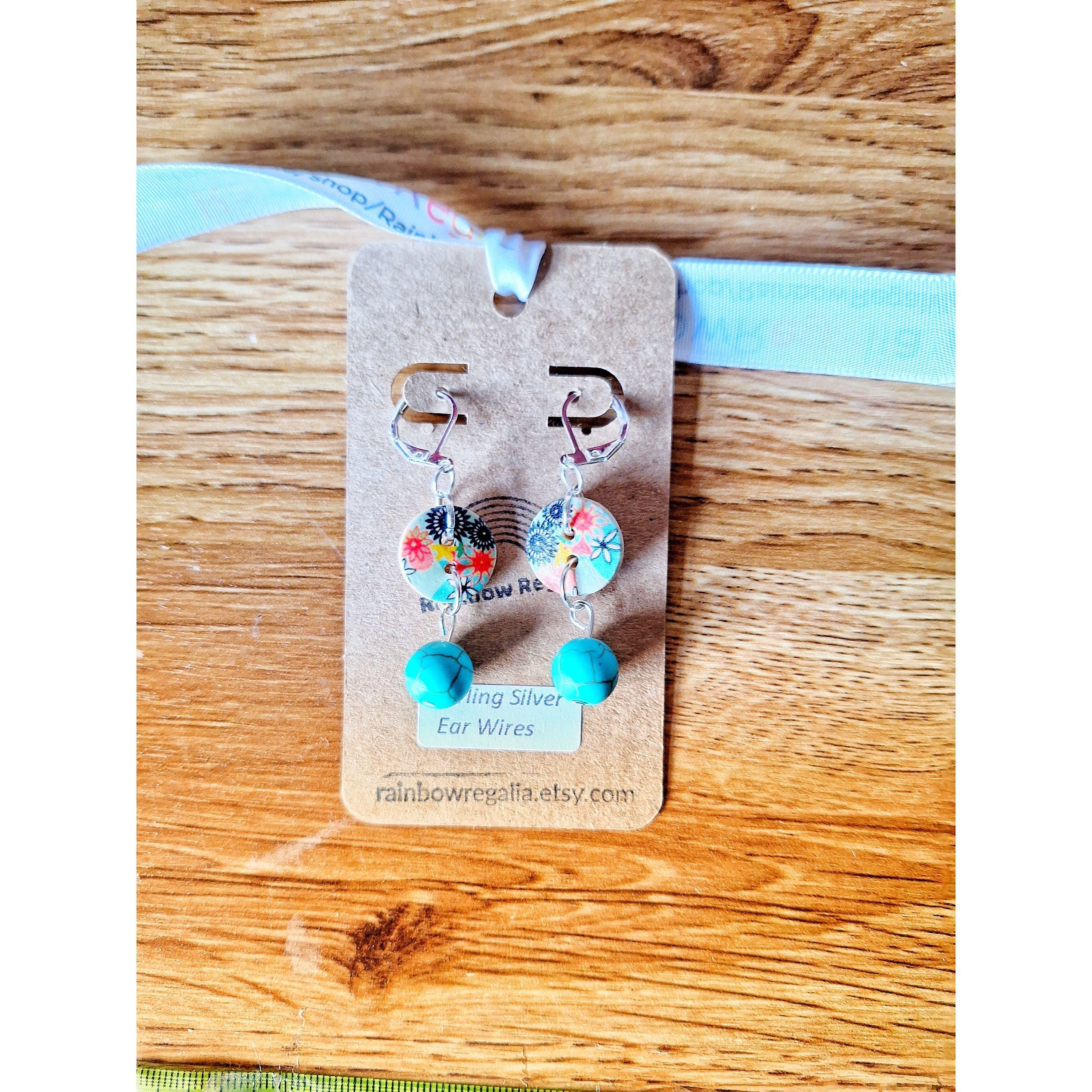 Fleur Drop Earrings with turquoise stones and wooden buttons on a wooden background.