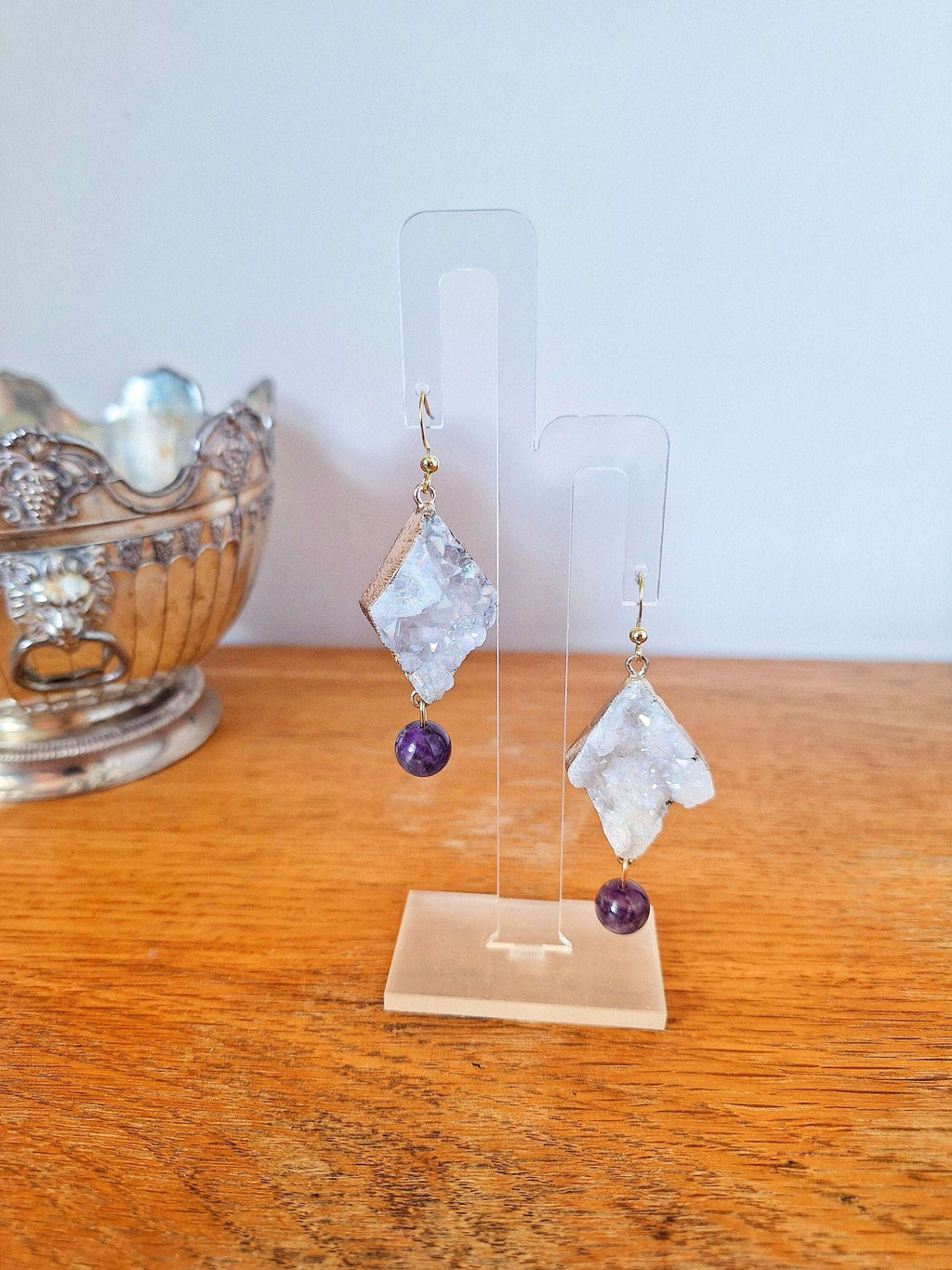 Aphrodite Quartz and Amethyst Earrings with gold-plated accents on display stand.