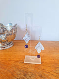 Aphrodite Quartz and Amethyst Earrings with gold-plated accents on display stand.