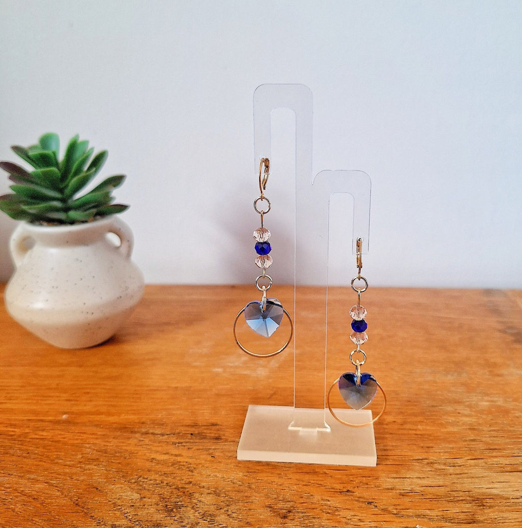 Amy Blue Heart Earrings with blue and pale pink glass beads, gold-plated hoops, on display stand.